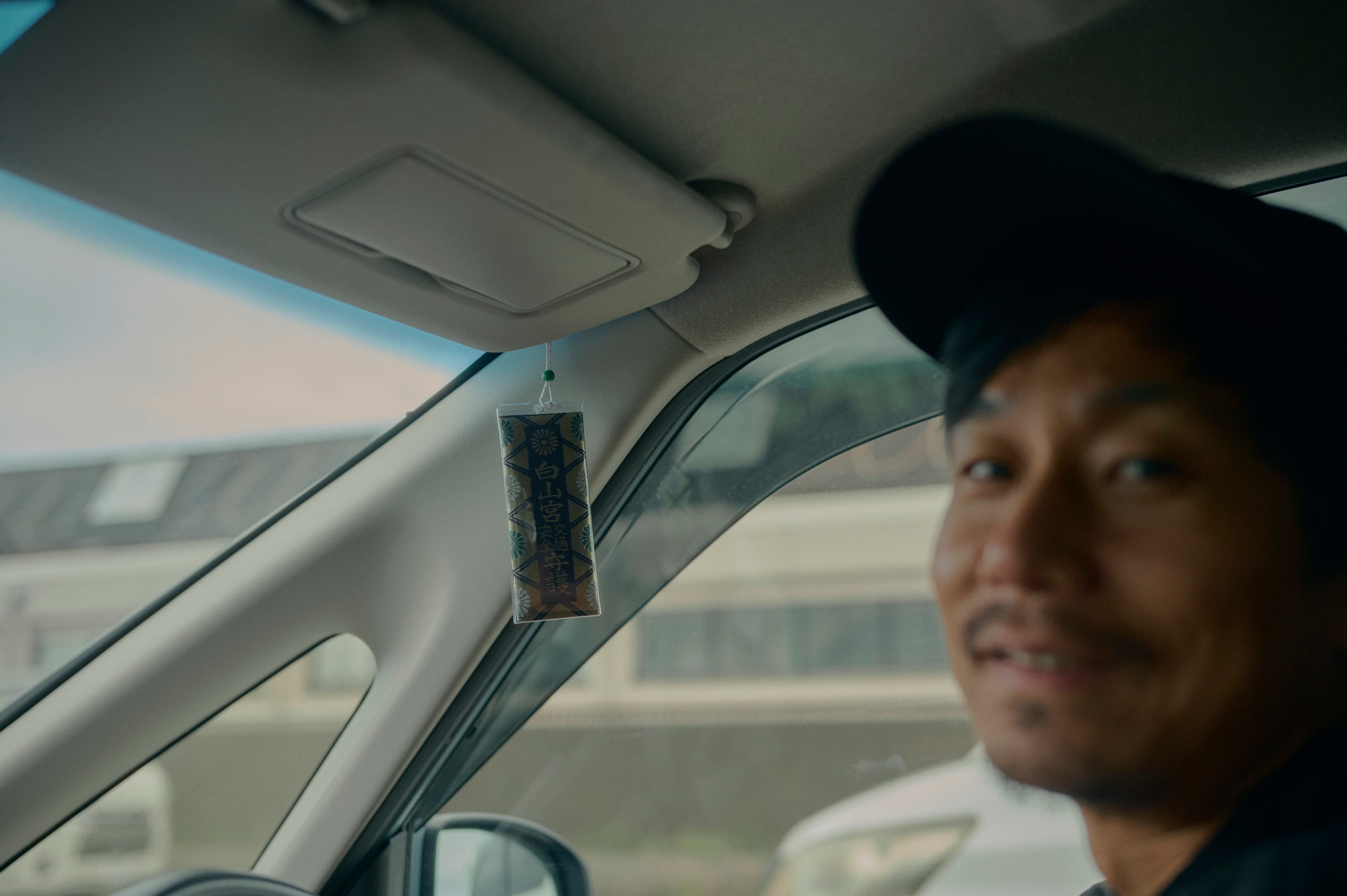 車内の右側にぼんやりと写る人物と、窓の向こうの風景