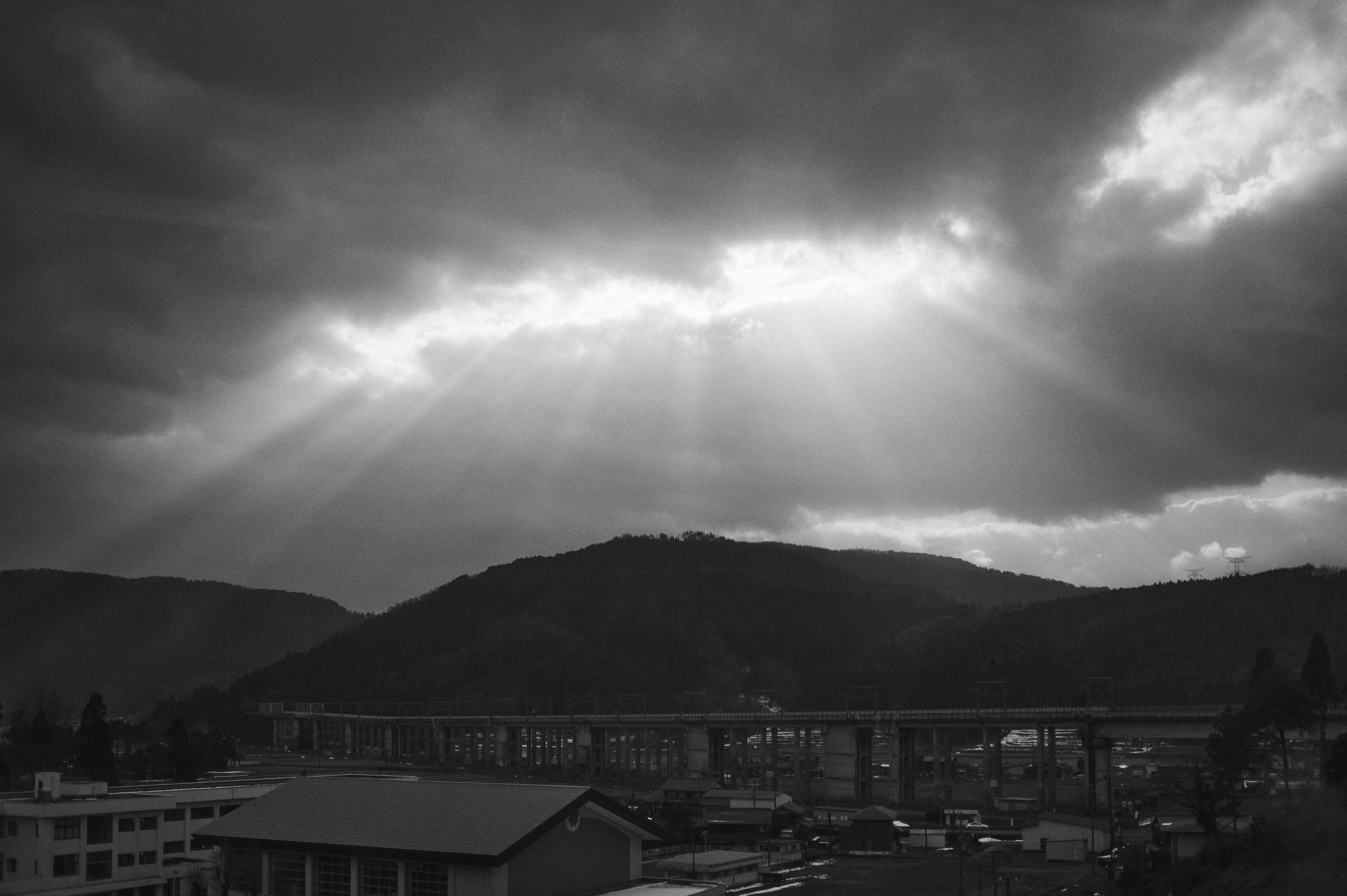 雲間から光芒が差すモノクロの山並み
