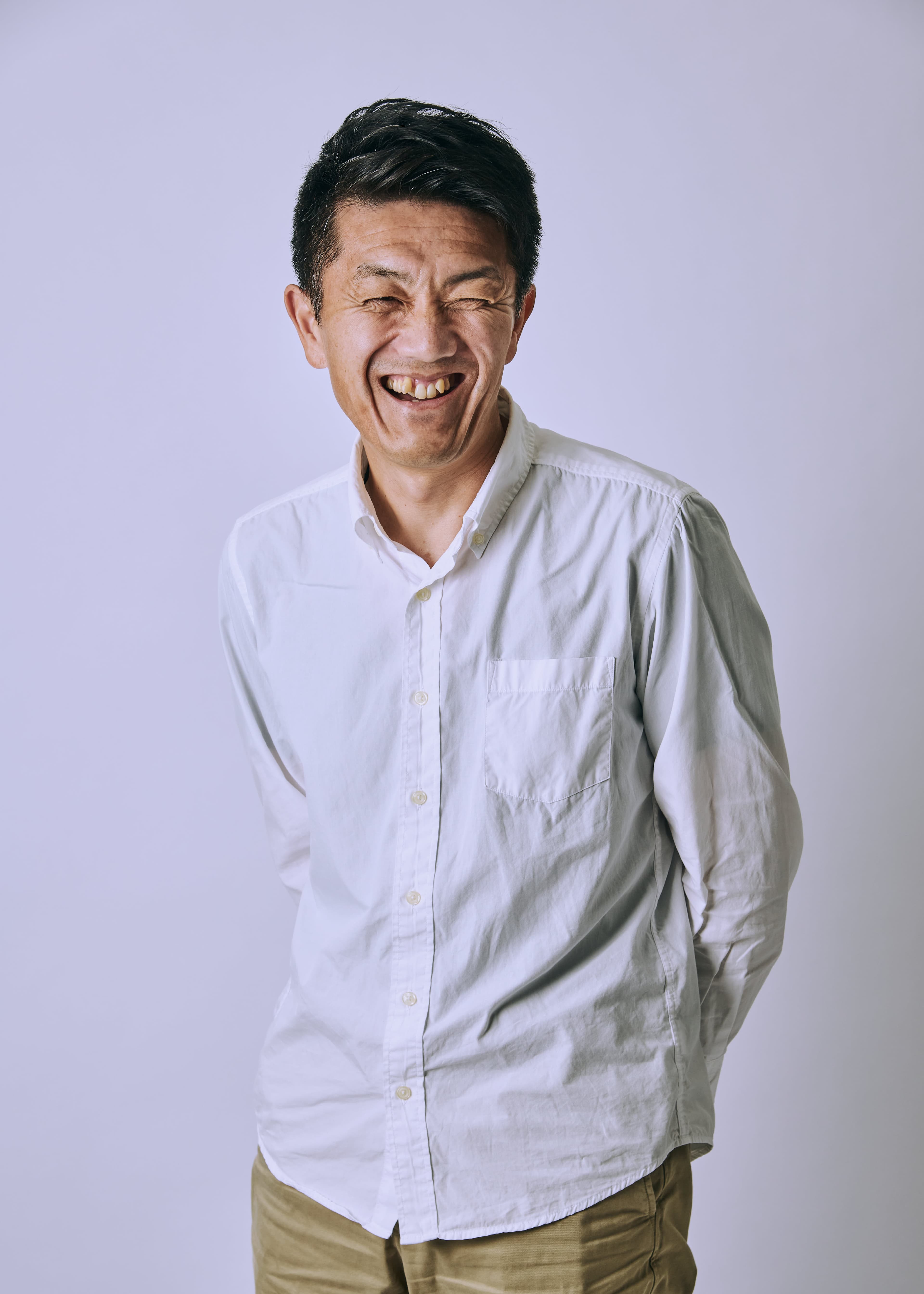 白い背景の前で笑う男性