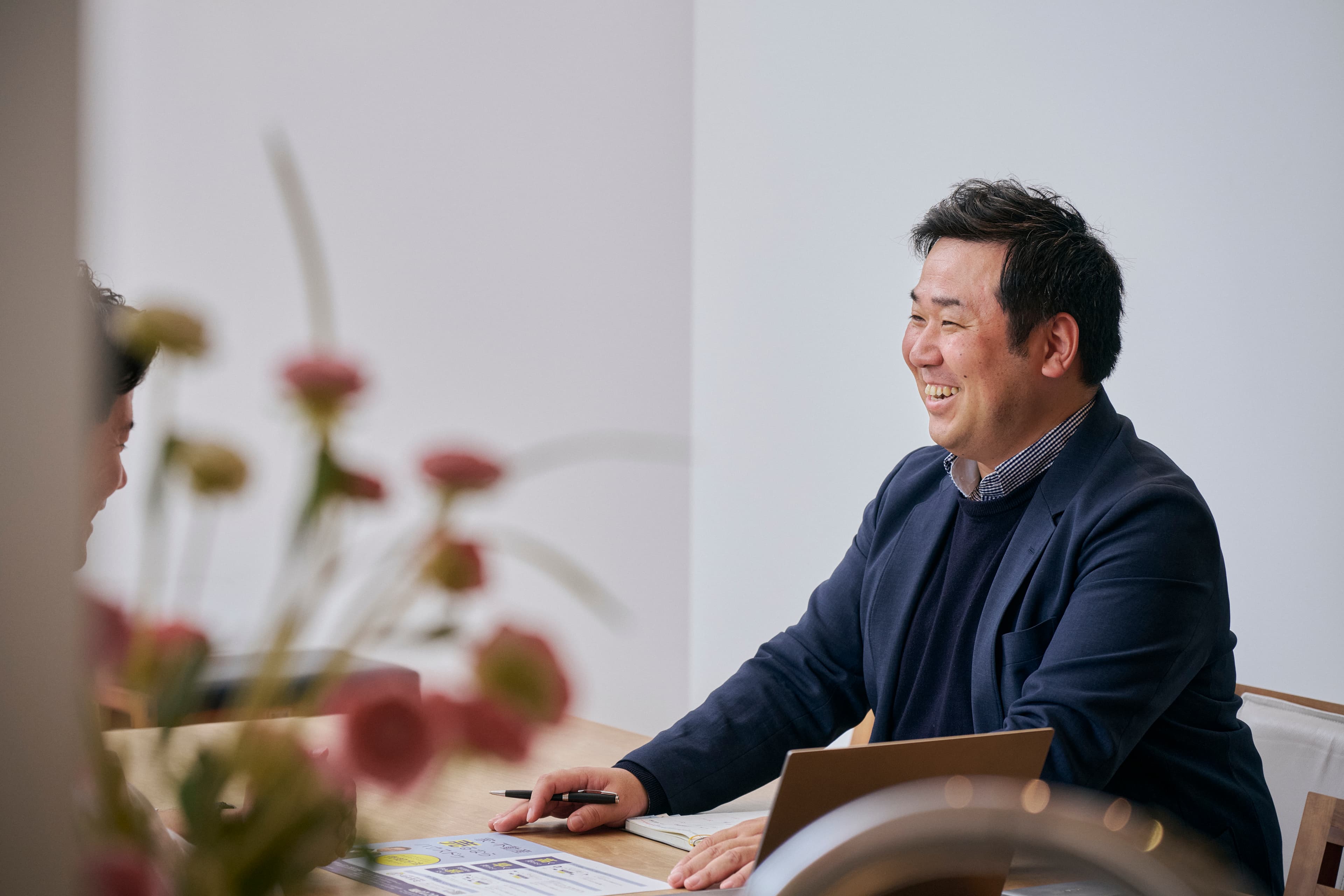 花と机を挟んで会話する男性
