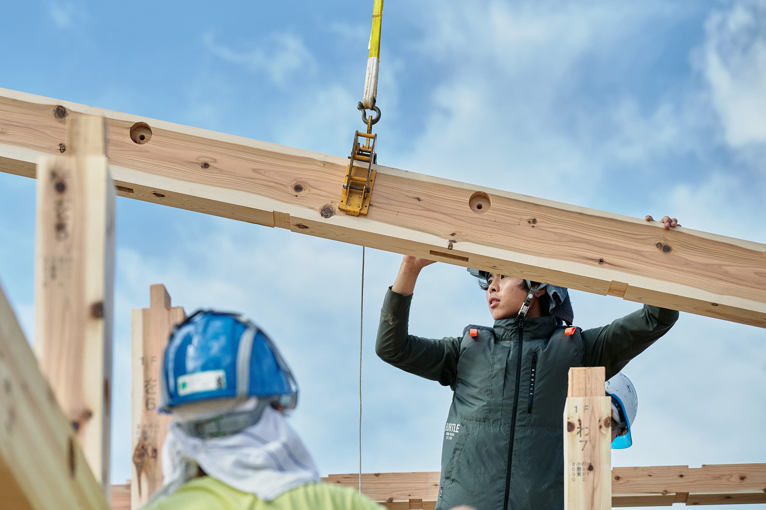 建築現場で協力して梁を扱う人々