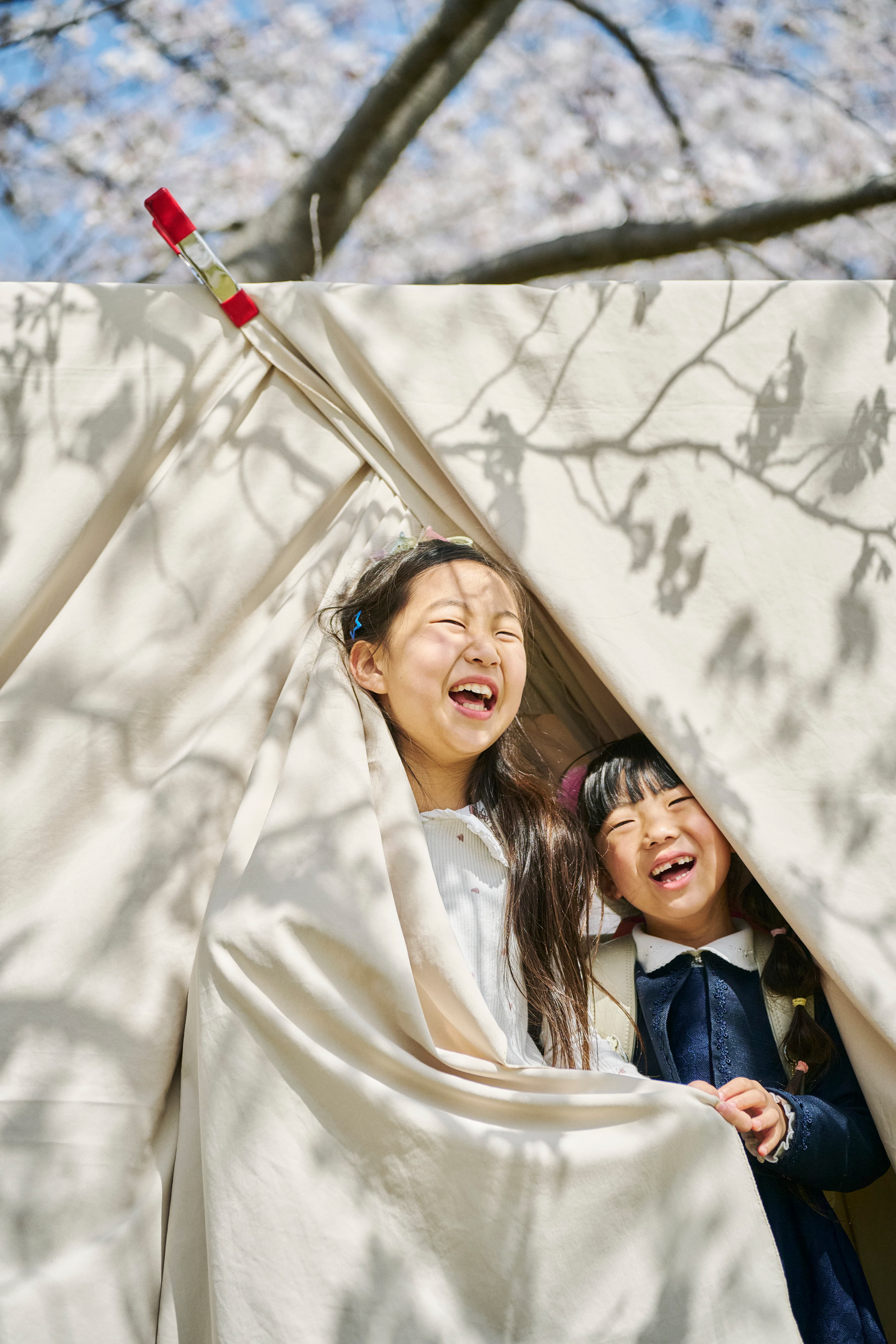 布の中から笑う二人の子ども