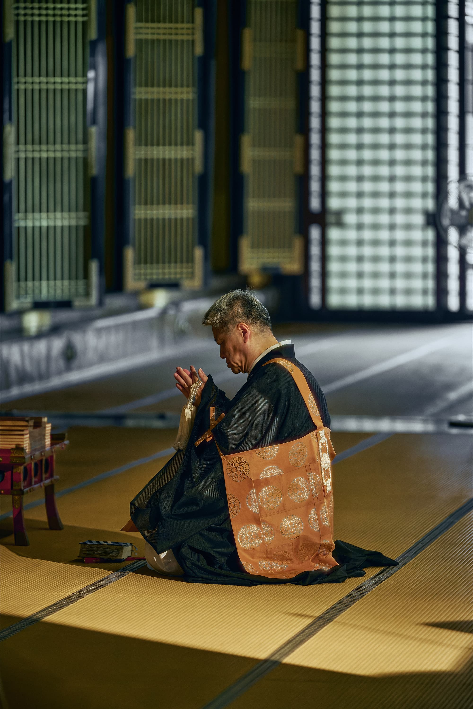 畳の上で祈る人物