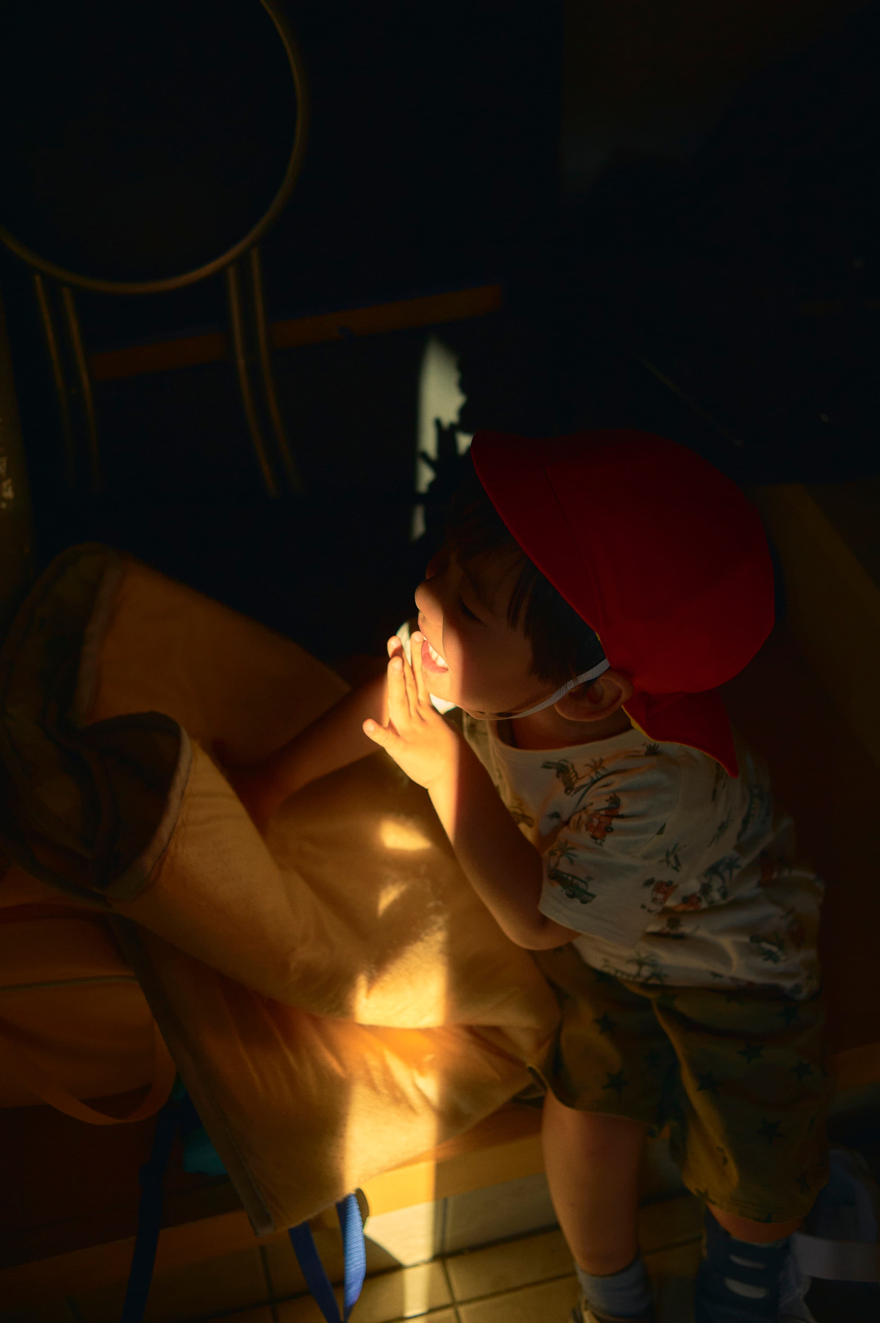 暗い室内で光を見つめる子ども