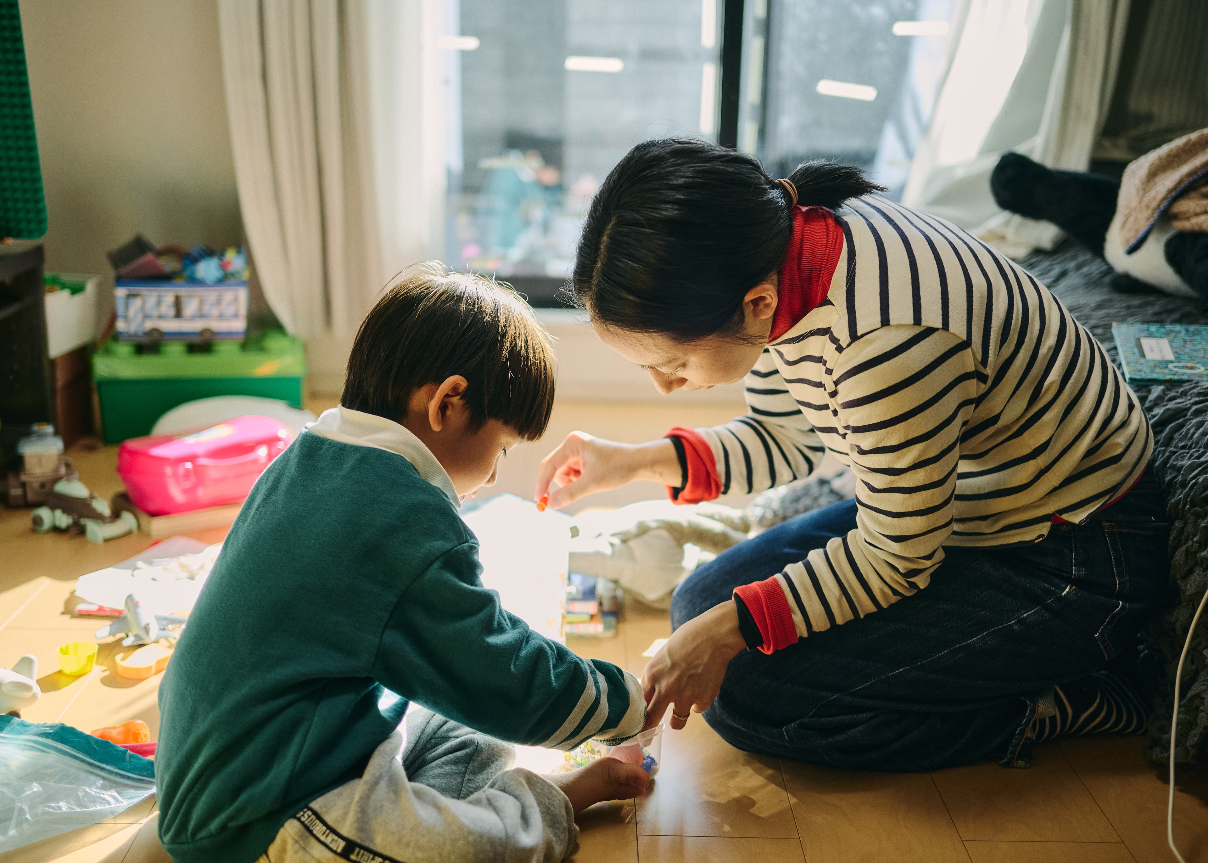 床に広げたものを囲む母親と子ども