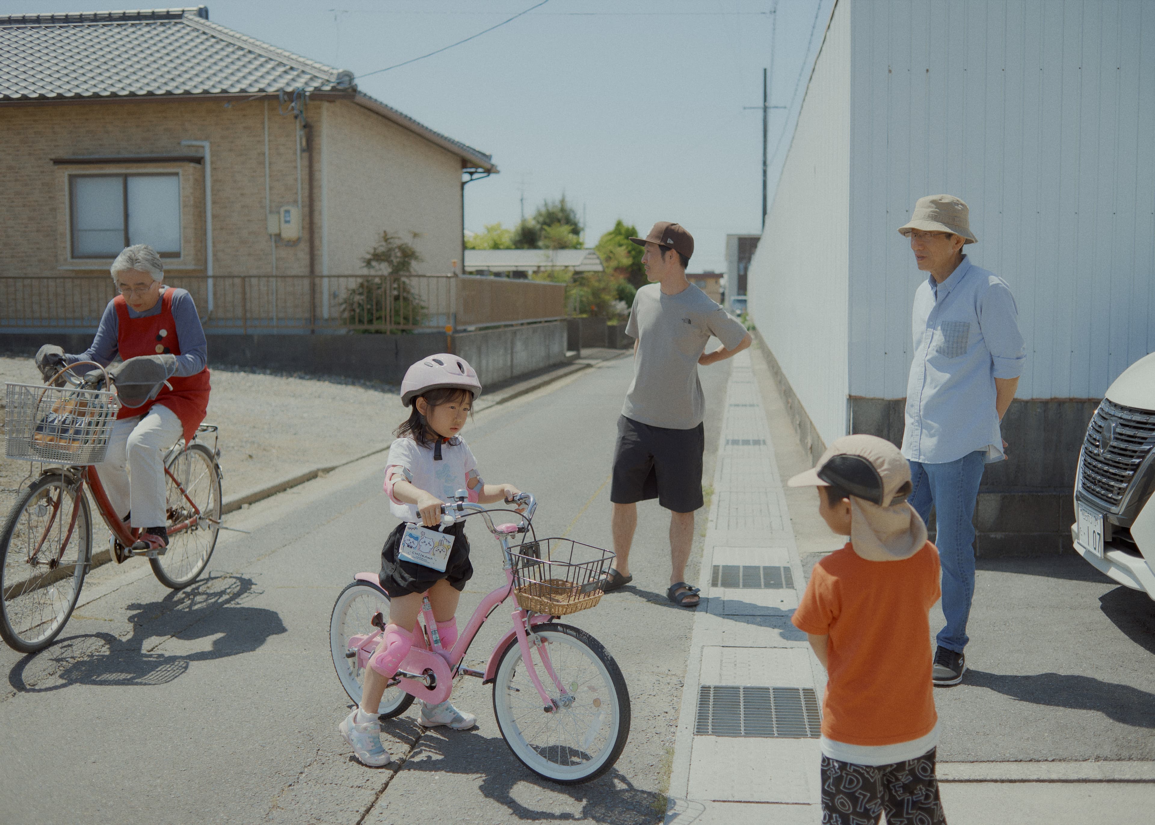自転車に乗る子どもたちと道に集まる人々