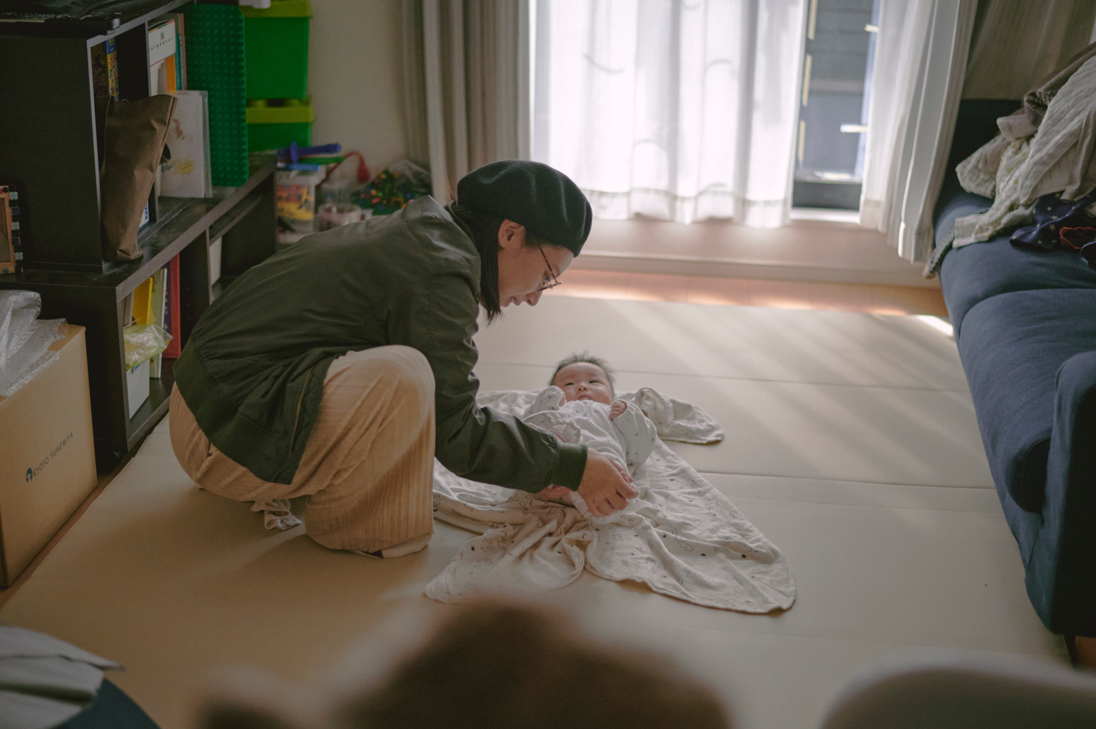室内の床に広げた紙に向かう親子
